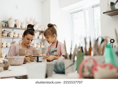 A mother and daughter enjoy pottery making together in a bright studio - Powered by Shutterstock