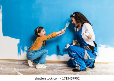 Mother and daughter enjoying together while painting wall. - Powered by Shutterstock