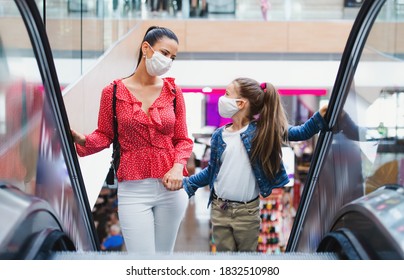 Mother and daughter with face mask on escalator indoors in shopping center, coronavirus concept. - Powered by Shutterstock