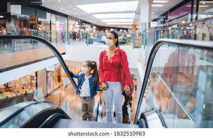 Mother and daughter with face mask on escalator indoors in shopping center, coronavirus concept. - Powered by Shutterstock