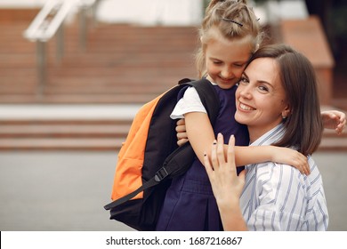 Mother And Daughter. Family Standing Near School. Mom Accompanies Her Child To School