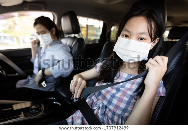 Mother and daughter fastening seat\
belt,woman sit in a car put on her seat belt for driving\
safety,child girl wearing a protective mask during the Coronavirus\
pandemic,spread of\
Covid-19,Protection