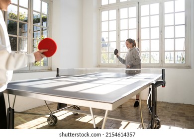 Mother and daughter feeling active while playing ping pong at home