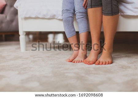 Mother and daughter feet on the white carpet