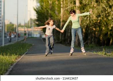 Mother with the daughter go on roller skates, outdoor, in the evening summer