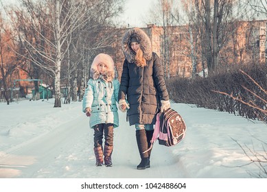 Mother And Daughter Go From School, Winter In The Park, Walking Family, A Child With A Backpack And A Young Mother