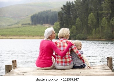 Mother, Daughter And Grandmother Sitting On A Jetty