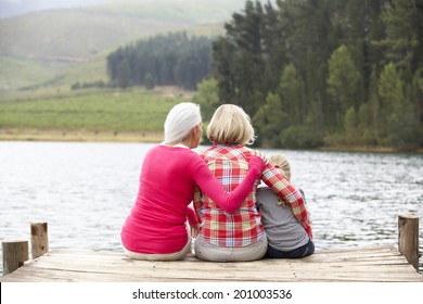 Mother, daughter and grandmother sitting on a jetty