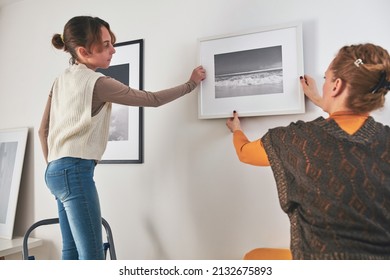 Mother and daughter hanging pictures and photos at home. - Powered by Shutterstock