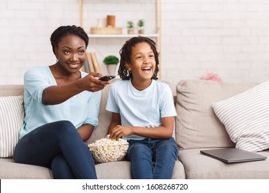 Mother With Daughter. Happy black family watching tv movie, cartoons or football with popcorn. Copy space