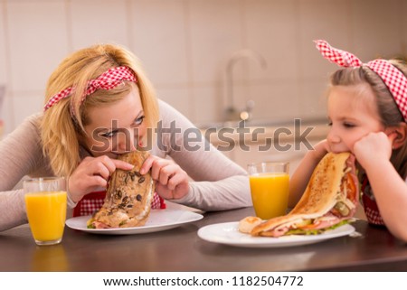 Mother and daughter having breakfast in the kitchen; daughter refuses to eat. Focus on the mother