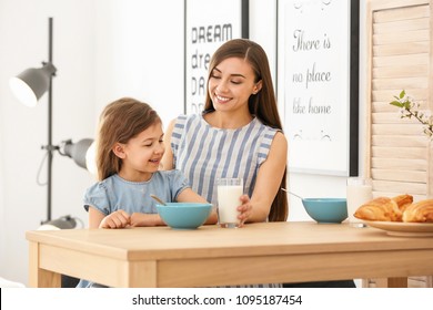 Mother And Daughter Having Breakfast With Milk At Table