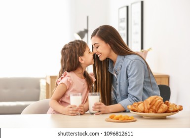 Mother And Daughter Having Breakfast With Milk At Table