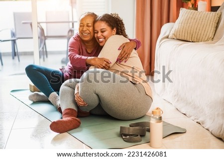 Mother and daughter having fun doing fitness exercises at home - Family and sport concept in winter time - Focus on senior woman hands
