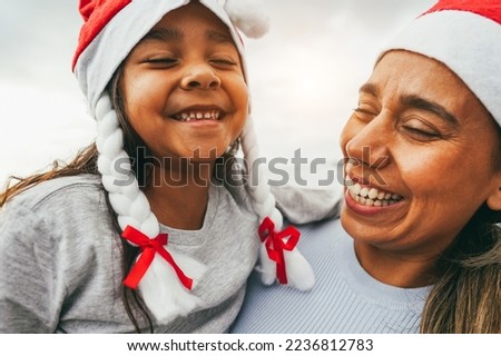 Mother and daughter having fun during Christmas time wearing Santa Claus hats - Family and holidays concept