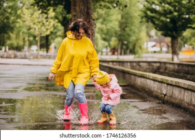 Mother with daughter having fun jumping in puddles - Powered by Shutterstock