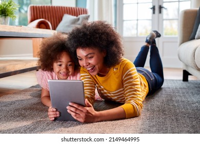 Mother And Daughter Having Fun Lying On Floor Streaming Movie On Digital Tablet At Home Together - Shutterstock ID 2149464995
