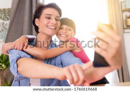 a mother and daughter having fun making a photography together at home