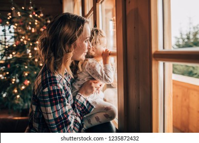 Mother And Daughter Having Fun On Christmas Morning. Precious Family Moment, Young Mom Playing With Her Toddler Daughter By The Window, Winter Landscape.