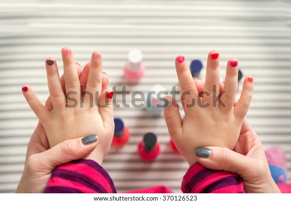 Mother and daughter having fun painting\
fingernails, family time concept, view from\
above
