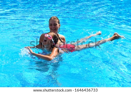 Mother and daughter having fun in the pool. Mother with girl on vacation. Happy holidays children. Funny summer vacation