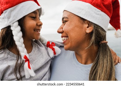 Mother and daughter having fun together during Christmas time wearing Santa Claus hats - Family and holidays concept - Main focus on mother face