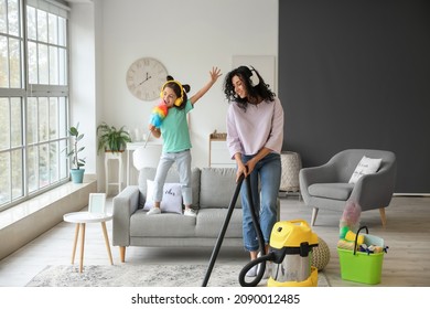 Mother And Daughter Having Fun While Hoovering Floor In Flat