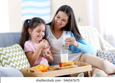 Mother and daughter having healthy breakfast on sofa in room - Powered by Shutterstock