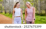 Mother, daughter and holding hands in forest with hiking for fitness adventure, sightseeing or laughing. Bonding, mature woman or girl in woods with walking, holiday travel or talking on outdoor path