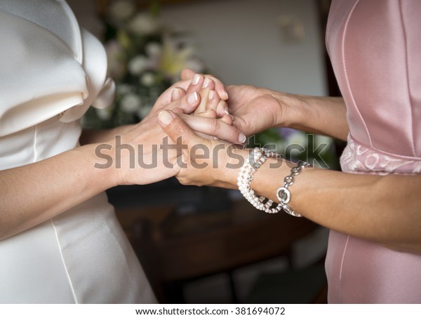 mother and\
daughter holding hands on her wedding\
day