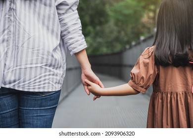 Mother And Daughter Holding Hands At Outdoor. Close Up Shot Of Caucasian Woman Hand Holding Little Girl's Hand While Walking Outdoors. Mother Holds Her Daughter's Hand. Love And Care.