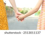 Mother and daughter holding hands outdoors, closeup