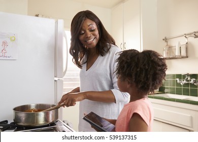 Mother And Daughter At Home Preparing Meal In Kitchen