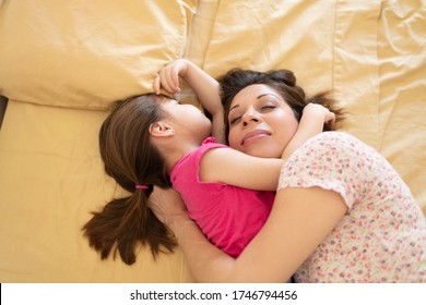 Mother And Daughter Hugging Each Other While Sharing A Bed And Cosleeping At Home