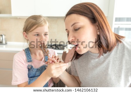Mother with daughter in kitchen eating ice cream. Good relations of parent and child. Happy family concept
