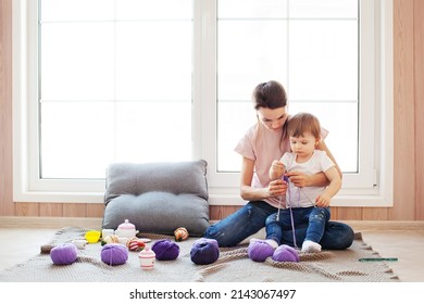 Mother And Daughter Knit. Mom Dark Hair Female Teach Child Crafting. Craft And Hobby For Family With Children. Toddler Girl Kid With Purple Yarn At Home, Lifestyles