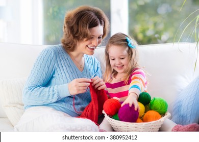 Mother and daughter knitting woolen scarf. Mom teaching child to knit. Crafts and hobby for parents and kids. Toddler girl kid with wool yarn in a basket. Knitted clothing for family with children.  - Powered by Shutterstock