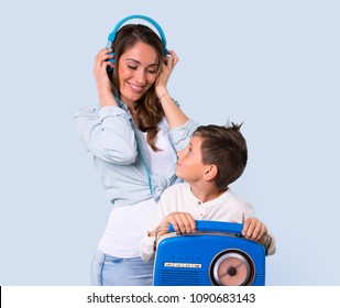 Mother And Daughter Listening To Music With Headphones And Radio On Blue Background