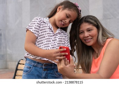 Mother With Daughter Looking At Cell Phone At Park