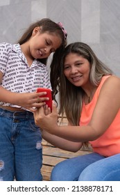 Mother With Daughter Looking At Cell Phone At Park