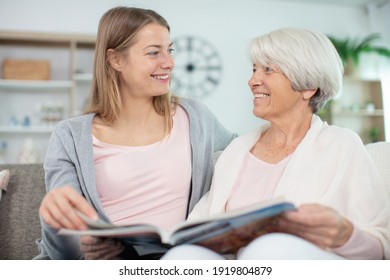 Mutter und Tochter, die das Fotobuch zwei Frauen zu Hause anschauen