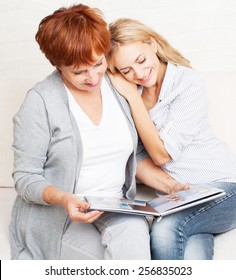 Mother And Daughter Looking Photo Book. Two Women At Home