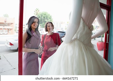 Mother And Daughter Looking At Wedding Dress In Shop Window