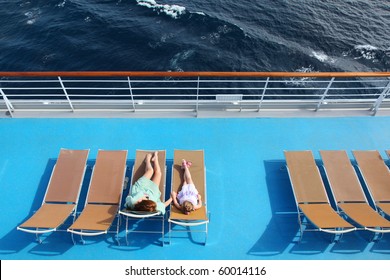 mother and daughter lying on beach armchairs on cruise liner deck, view from above