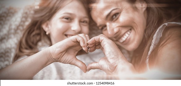 Mother and daughter making heart shape with hands while lying on bed at home - Shutterstock ID 1254098416