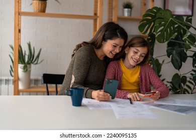 Mother and daughter making an online reservation.Joyful mom and her little excited daughter sitting at home and making an online reservation for a future trip.