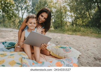 Mother and daughter making a video call at beach on sunny day - Powered by Shutterstock