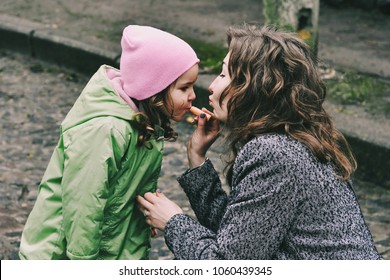 Mother and daughter. Mama put lip balm on daughters lips. Happy family. Amazing, laughing women. Happy mother's day. Casual lifestyle. Rainy spring day. First girls lipstick. 