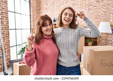 Mother And Daughter Moving To A New Home Holding Keys Smiling With An Idea Or Question Pointing Finger With Happy Face, Number One 