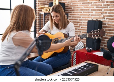 Mother and daughter musicians having spanish guitar class at music studio - Powered by Shutterstock